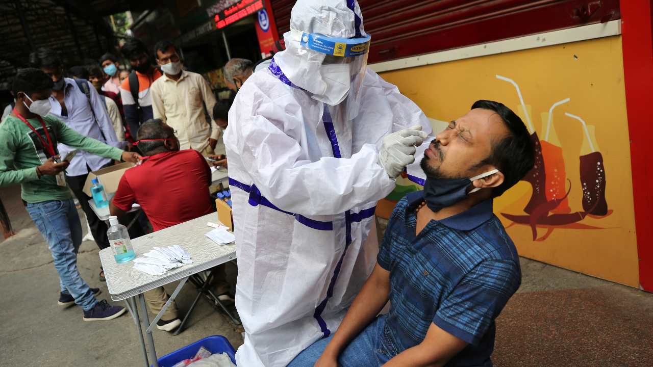 A health worker in a protective suit collects a passenger's nasal towel to perform a COVID-19 test outside a train station in Bengaluru, India, on Sunday, April 11, 2021. India reports an increase in inflammation, experts say, due in part to growing indifference to social distance and masks.  (AP Photo / Aijaz Rahi)